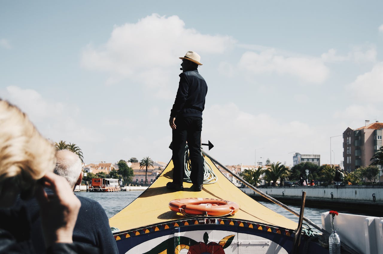 portfolio-04 Silhouetted man steering a gondola on a sunny canal, showcasing vibrant urban imagery.